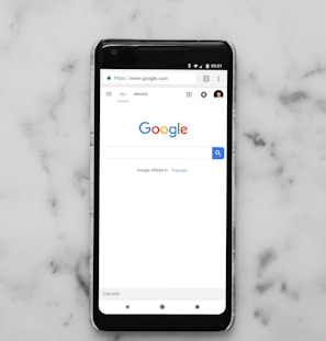 black Android smartphone showing google site on white surface