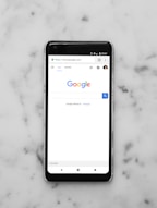 black Android smartphone showing google site on white surface