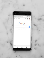 black Android smartphone showing google site on white surface