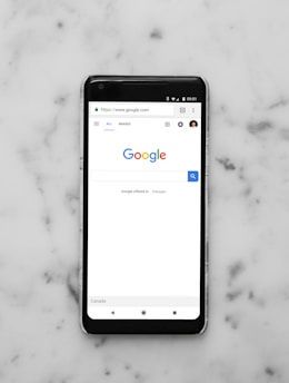black Android smartphone showing google site on white surface