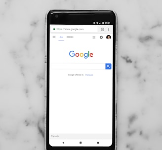 black Android smartphone showing google site on white surface