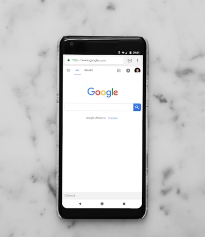 black Android smartphone showing google site on white surface