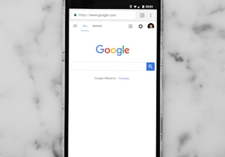 black Android smartphone showing google site on white surface
