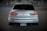 A silver sports car is prominently displayed from the rear, with distinctive tail lights and a dual exhaust. The car is parked in a dimly lit area, possibly a garage or an underpass, with murals visible in the background. The license plate indicates the vehicle is registered in Colorado.
