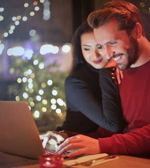 man and woman looking on silver laptop while smiling