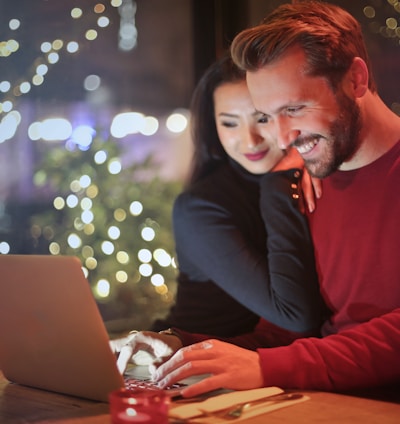 man and woman looking on silver laptop while smiling