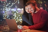 A couple happily reviewing their trip budget on a laptop in a cozy home setting.