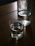 Close-up of a crystal-clear Shuddhi glass water bottle catching sunlight on a polished wooden table.
