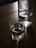 A glass of clear water placed on a wooden table with a green plant in the background.