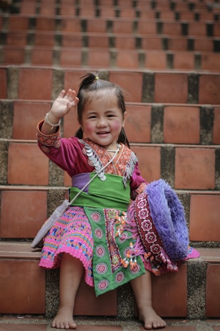 A Wayuu child smiling brightly in traditional colorful clothing in La Guajira.