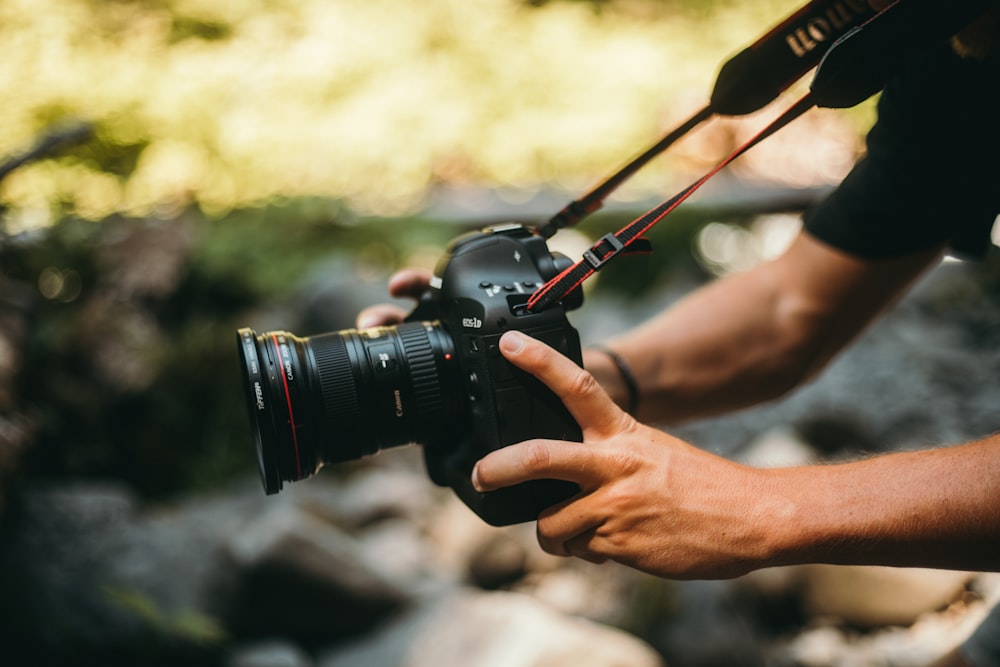 person holding DSLR camera while taking picture