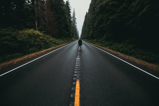 person walking alone in the middle of the road