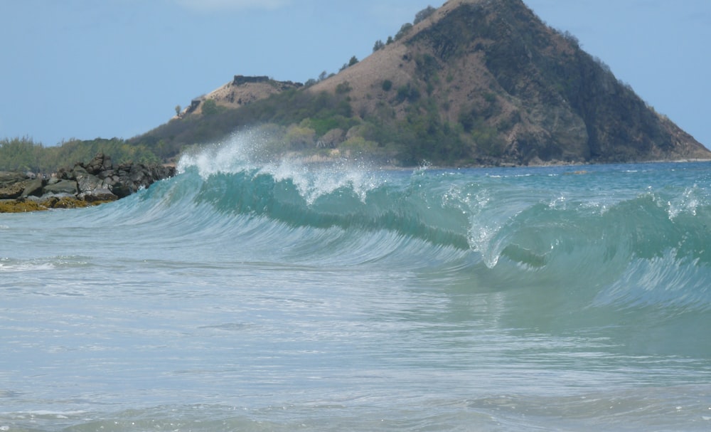 sea wave near mountain at daytime