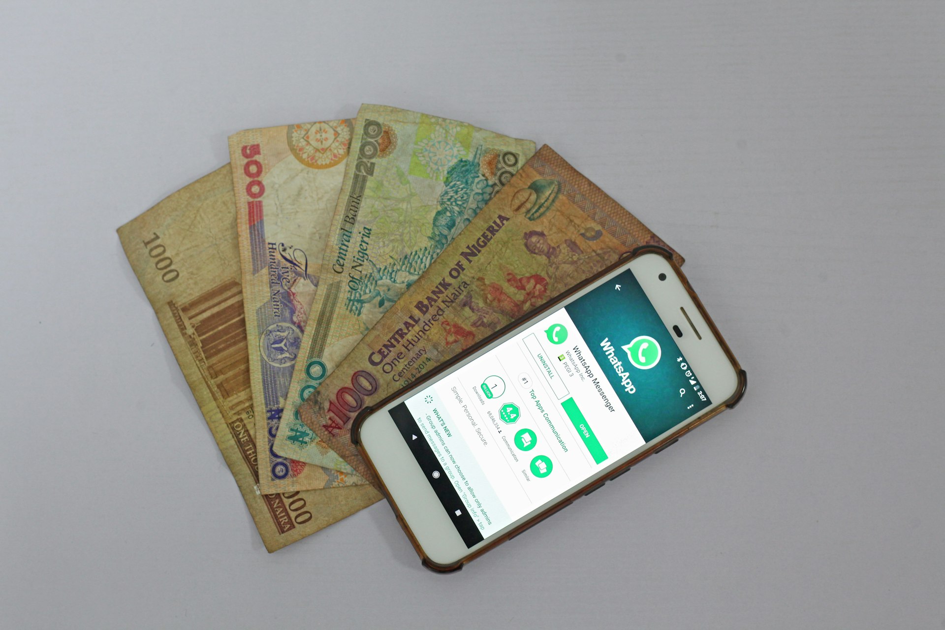 Nigerian Naira next to a used Android phone with WhatsApp.