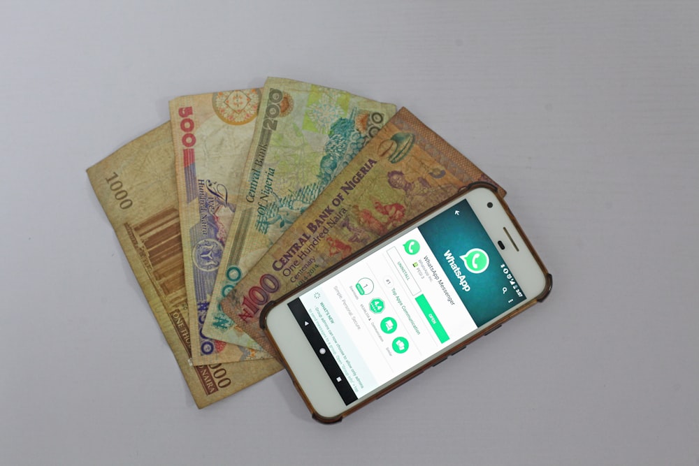white Android smartphone beside banknotes