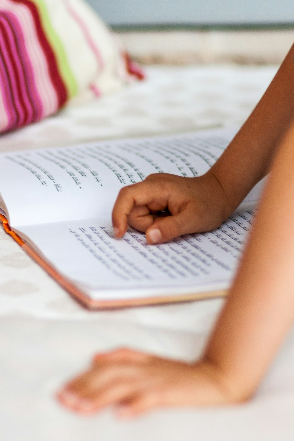 La mano de un niño apuntando en el libro de escritura devanagari