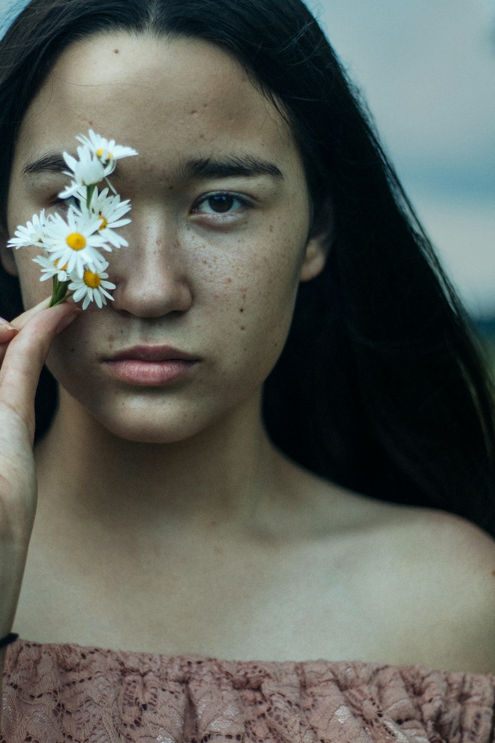 Frau bedeckt ihre Augen mit weißen Blumen