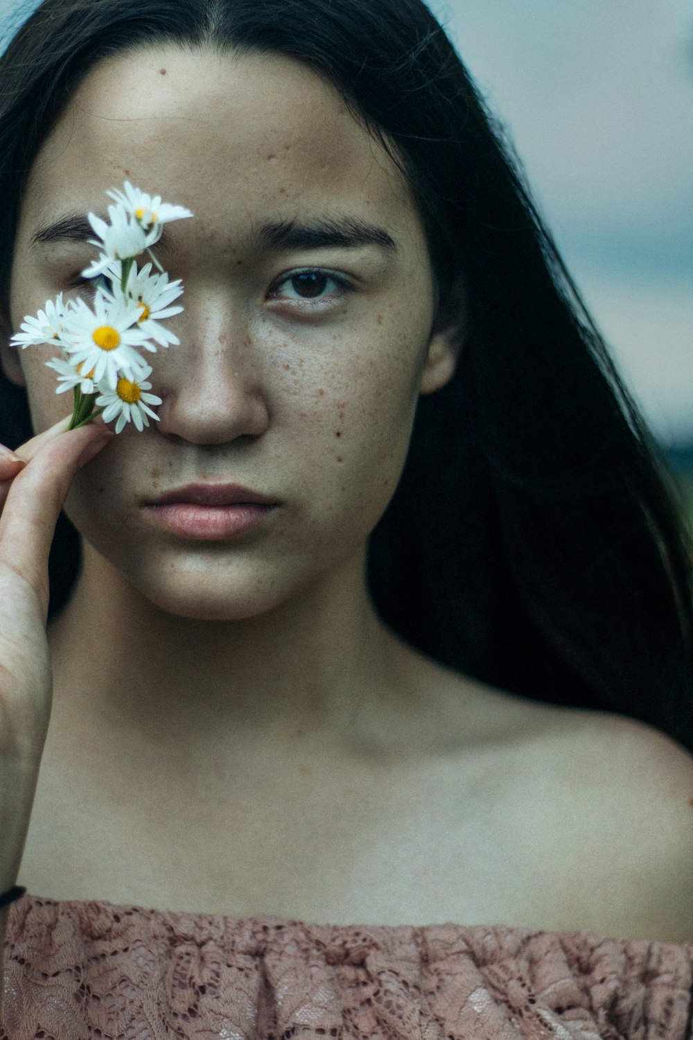 woman covering her eyes with white flowers