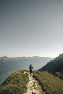 person hiking above mountain overlooking river