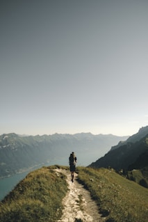 person hiking above mountain overlooking river