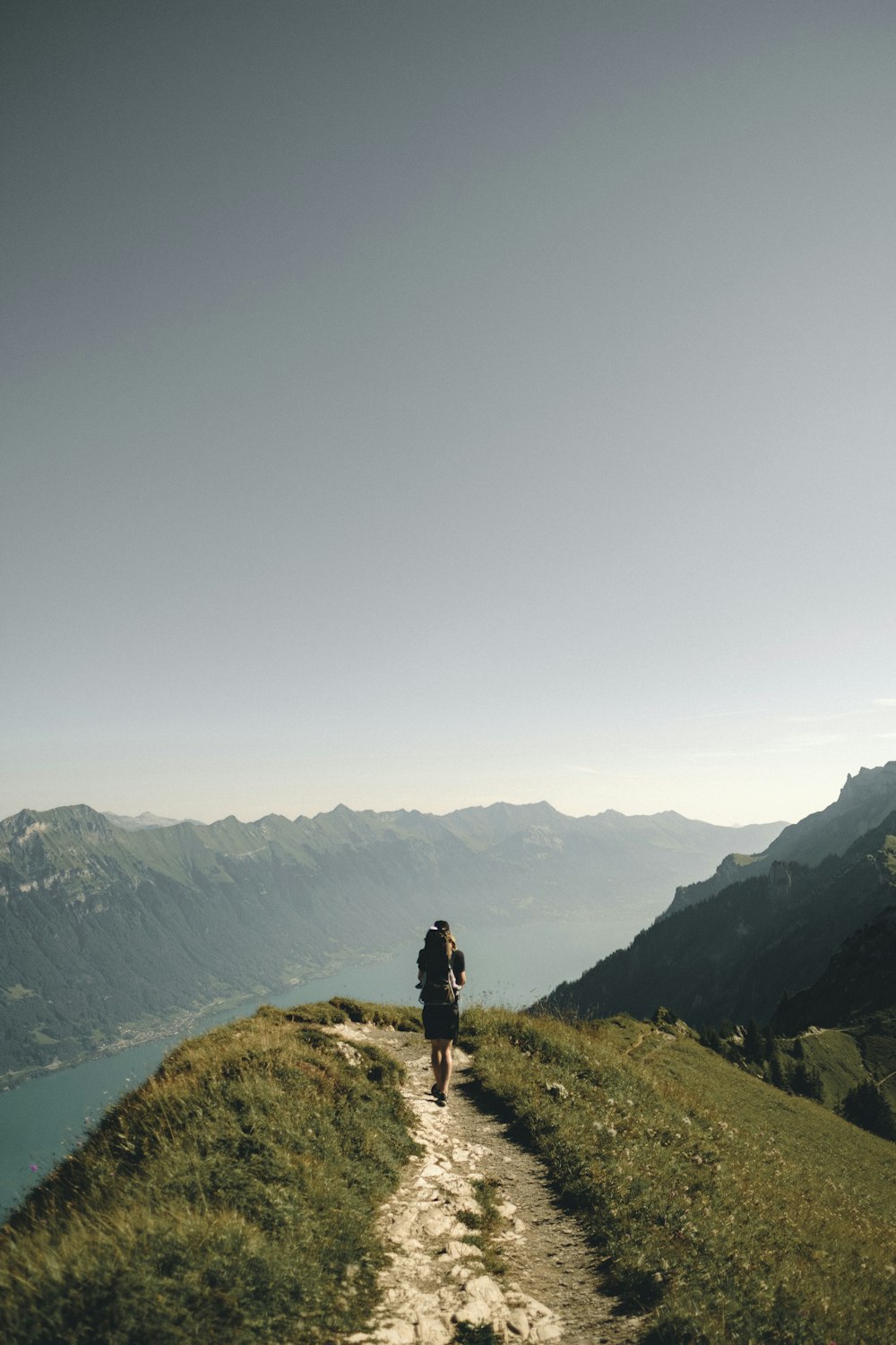 person hiking above mountain overlooking river