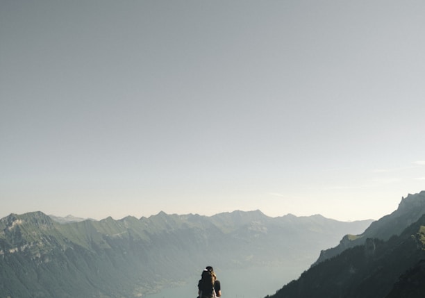 person hiking above mountain overlooking river