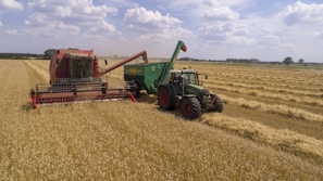 two green and red cultivators on brown field