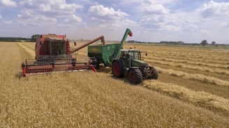 two green and red cultivators on brown field