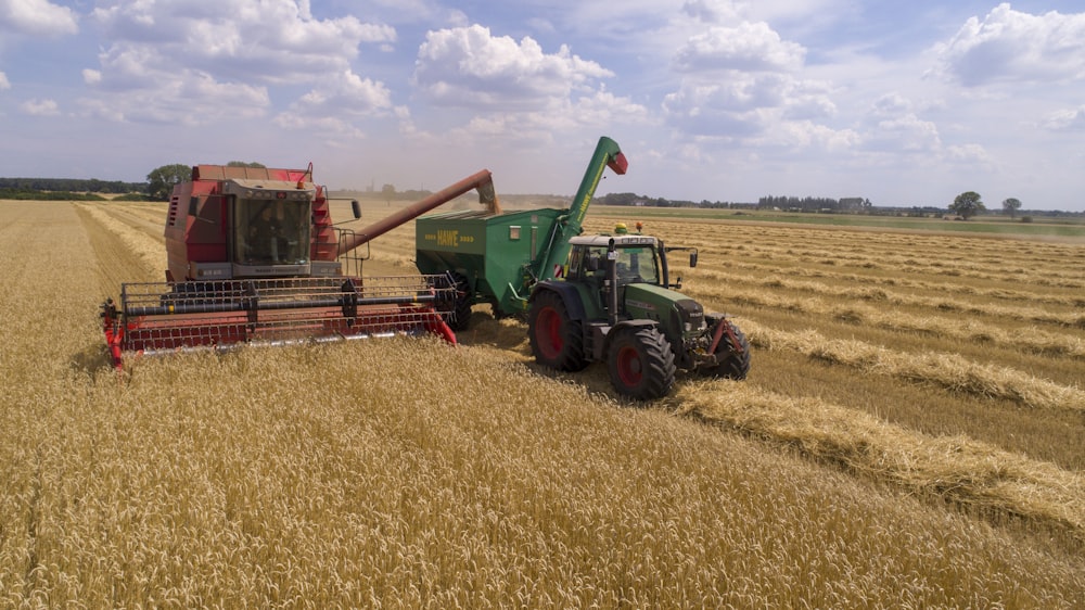 Dois cultivadores verdes e vermelhos no campo marrom