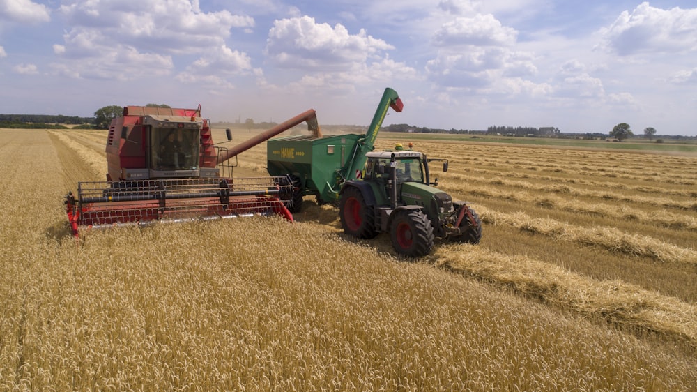 two green and red cultivators on brown field