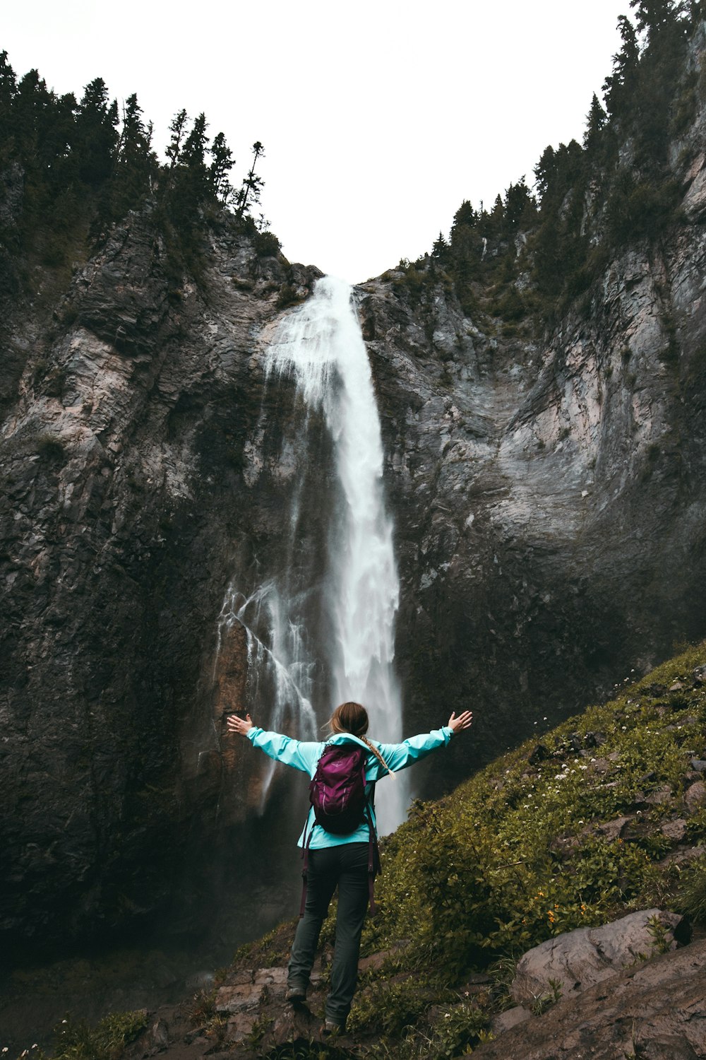 mulher em pé na colina de frente para cachoeiras