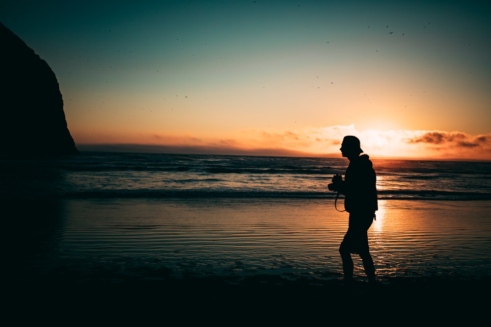 Hombre caminando por la orilla del mar en la hora dorada