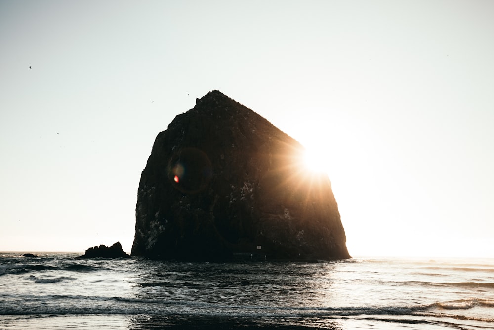 silhouette of rock formation surrounded with body of water