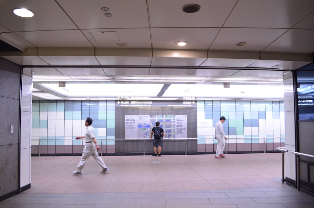 three person walking on train hallway