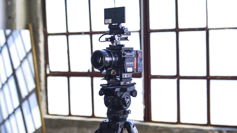 caméra de tournage noire sur trépied près de la fenêtre