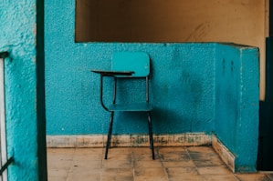 blue and black writing chair beside wall