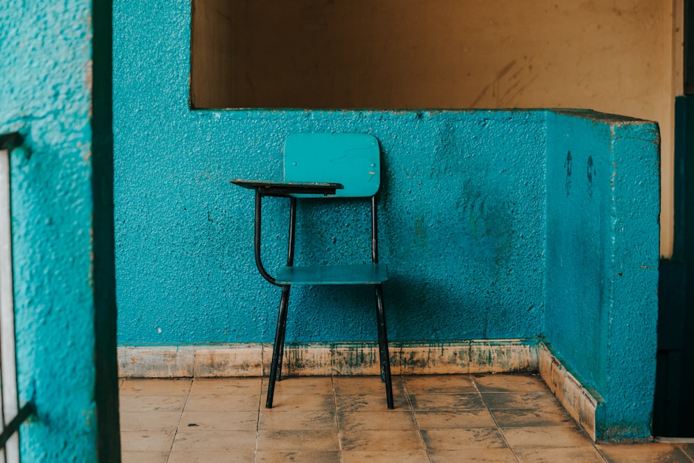 blue and black writing chair beside wall
