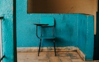 blue and black writing chair beside wall