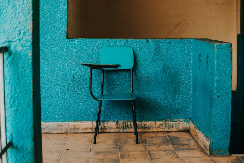 Chaise d’écriture bleue et noire à côté du mur