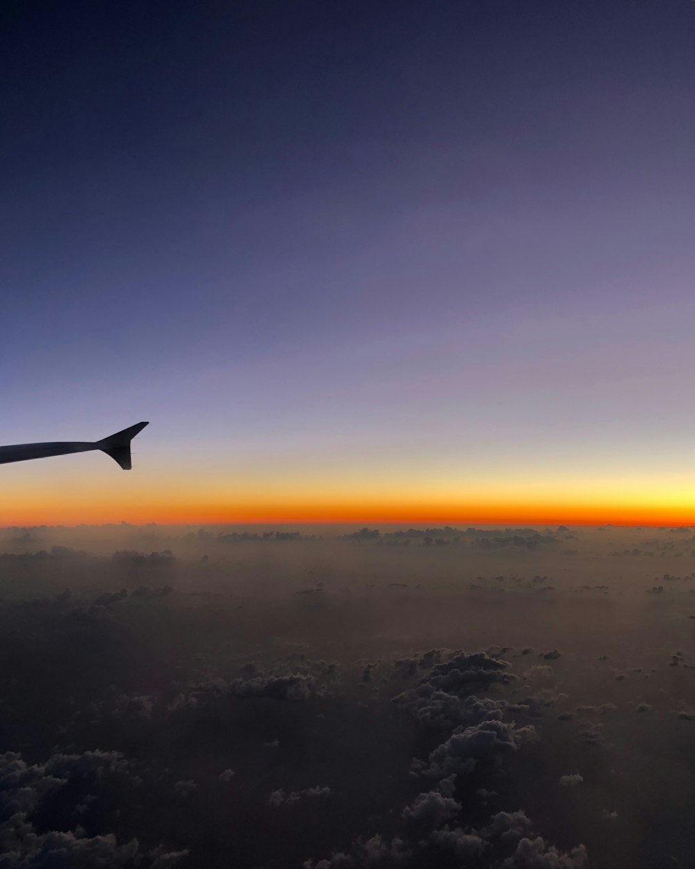 a view of the wing of an airplane as the sun sets