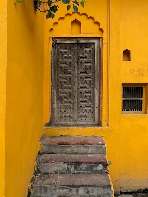 A rustic wooden doorstep adorned with a hand-painted mat showcasing a leafy vine design.