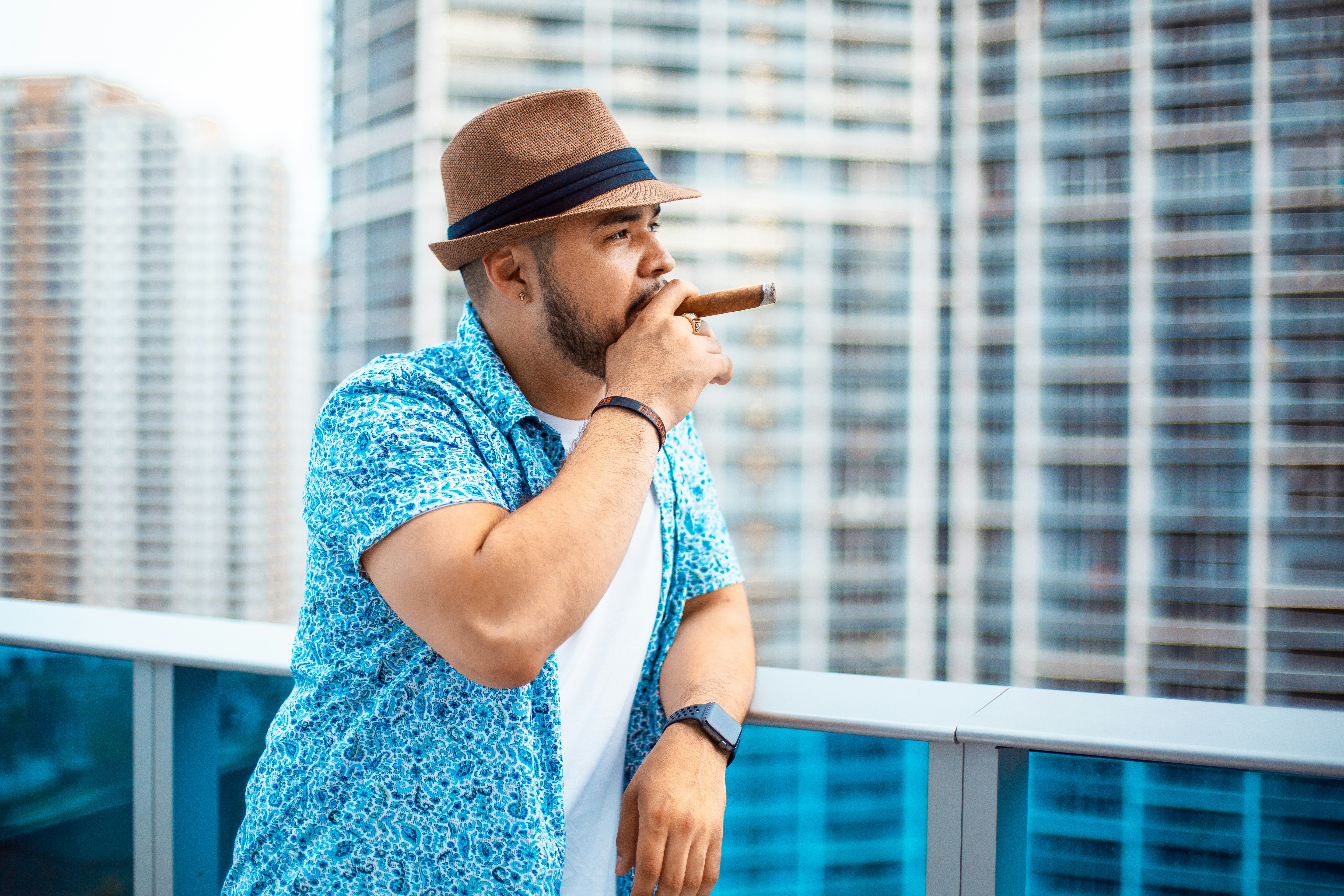 person leaning against white metal railing while smoking cigar