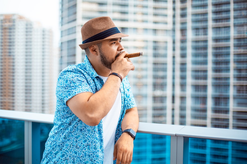 person leaning against white metal railing while smoking cigar