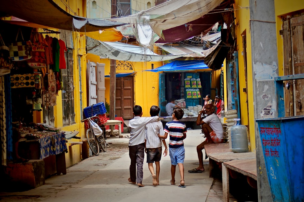 três meninos caminhando entre prédios durante o dia