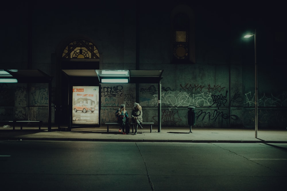 two people sitting on waiting bench