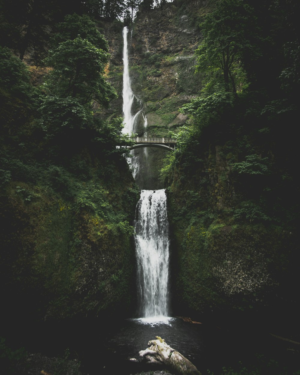 waterfall in between mountains with bridge