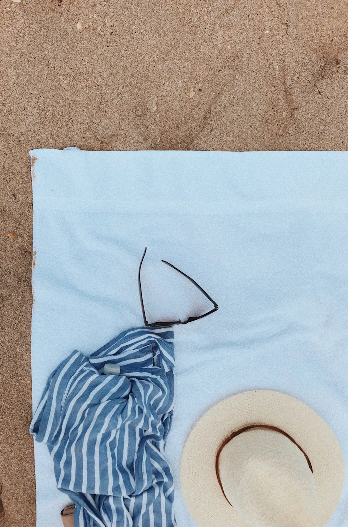 Flat-lay of a sun hat and sunglasses on a beach towel