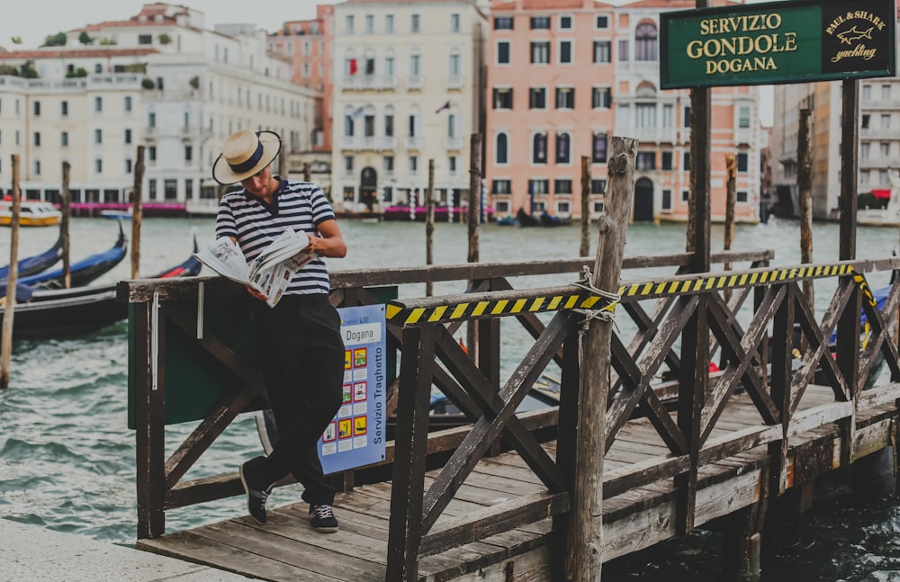 man standing on brown wooden boat dock