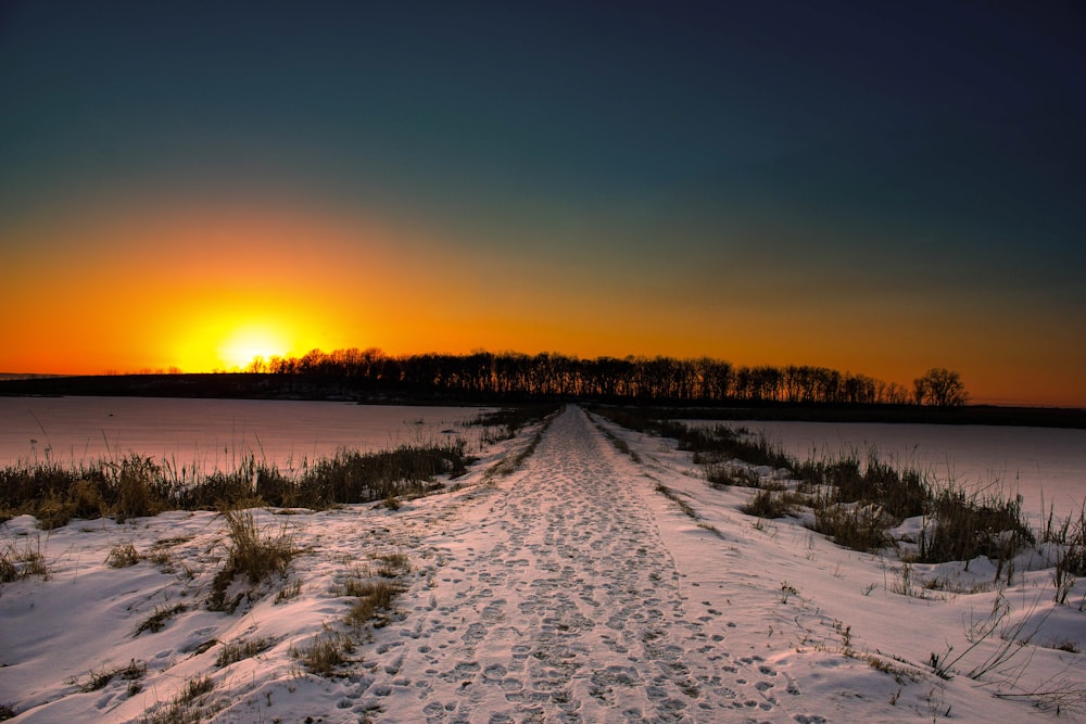 white snow covered road during sunrise