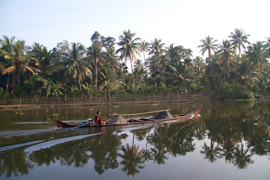 person riding on boat while sailing on body of water in Alappuzha India